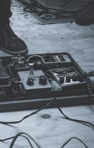 "Various guitar pedals arranged on a pedalboard with cables, showcasing a diverse selection of effects for musicians."